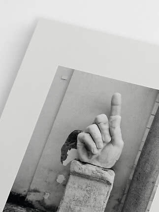 Sort-hvid plakat med skulptureret hånd på sokkel med langfinger løftet