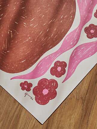 Nahaufnahme eines abstrakten Prints mit brauner Form, rosa Wellen und Blumen auf Holzboden