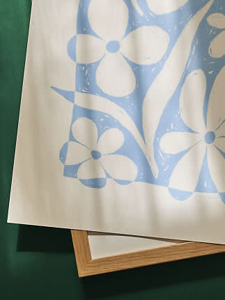 Blue and white floral art print on paper, partly covering a light wood frame.