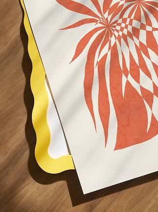 Affiche à motif floral abstrait orange sur papier blanc, sur fond jaune ondulé, posée sur un sol en bois