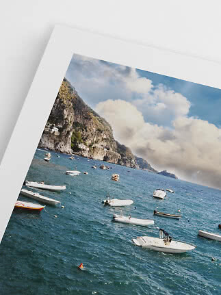Framed photo print of a coastal cliff with boats on the sea under a cloudy sky