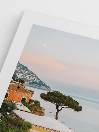 Printed coastal photo with house, tree, sea and mountain under a pale sky