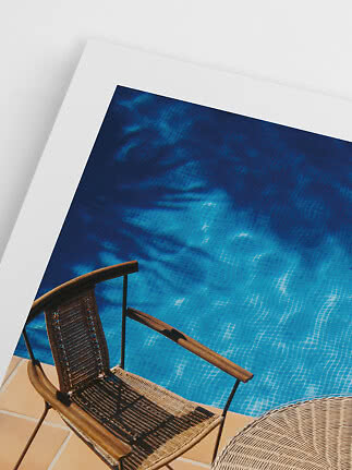 Woven chair beside a bright blue pool, viewed from above