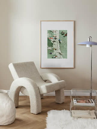 Affiche de surf encadrée au mur au-dessus d’un fauteuil crème dans une pièce moderne claire
