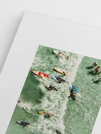 Tirage photo vue aérienne de surfeurs et paddleboards dans les vagues d’une mer turquoise.