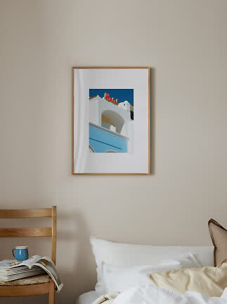 Bedroom with bed, wooden chair, and framed hotel print on beige wall
