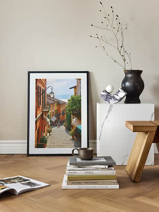 Framed photo poster of a sunny stepped street, leaning against a wall in a stylish interior