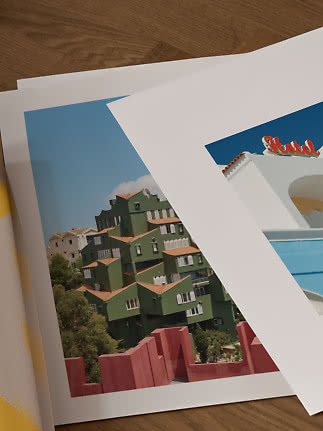Two overlapping architectural art prints on a wooden table