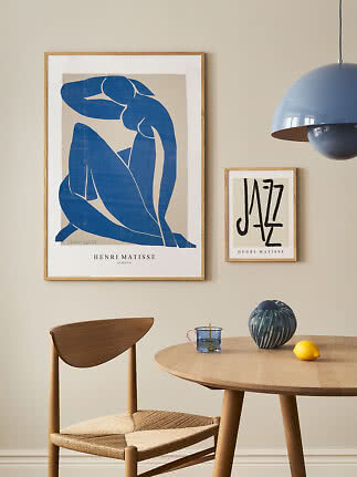 Spiseplads med stor blå Matisse-plakat, lille Jazz-plakat, træstol, rundt bord, vase og citron
