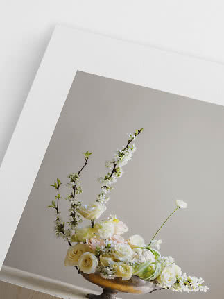Elegantes Blumenarrangement mit weißen Rosen und blühenden Zweigen in goldener Schale