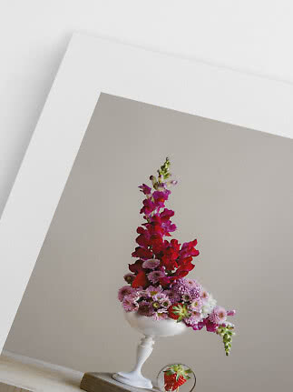 Asymmetrisch bloemstuk in witte vaas met roze en rode bloemen en aardbeien