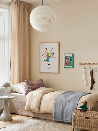 Mysigt barnrum med säng, beige gardiner och vit rund pendellampa i papper