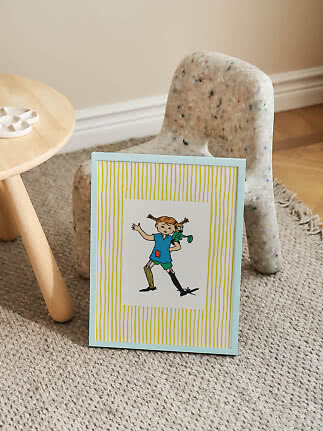 Inramad Pippi Långstrump-bild lutad mot en liten spräcklig stol på en matta