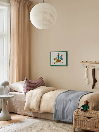 Accogliente cameretta con letto singolo, lampada a sospensione in carta, tende beige e panca in rattan