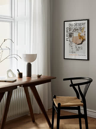 Indrammet kunstplakat på beige væg over træbord ved vindue i lys, minimalistisk stue