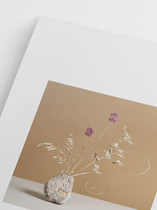 Decorative stone-shaped vase with dried grasses and purple flowers against a beige backdrop