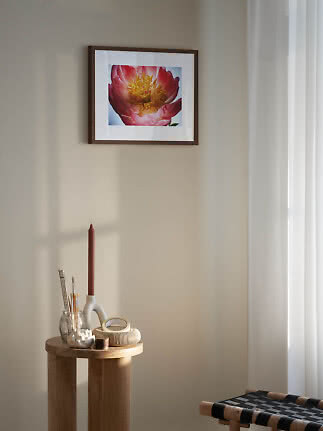 Affiche florale encadrée avec fleur rose sur mur beige au-dessus d'une petite table en bois