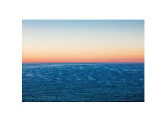 Mer calme sous un ciel pastel au coucher du soleil