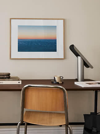 Bureau minimaliste avec chaise, lampe et photo de mer encadrée au mur