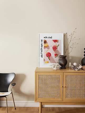 Buffet en bois clair à portes cannées, affiche, vase foncé et déco contre un mur beige