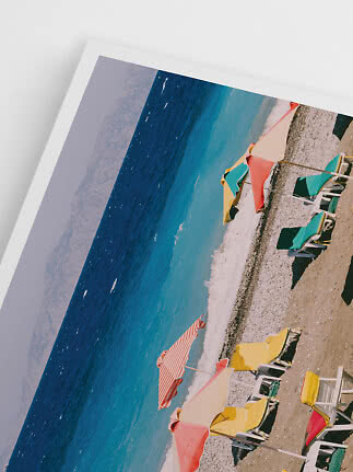 Gerahmtes Foto eines Strands mit bunten Sonnenschirmen und Liegen am türkisblauen Meer