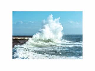 Grandes olas rompiendo contra un muelle bajo un cielo azul
