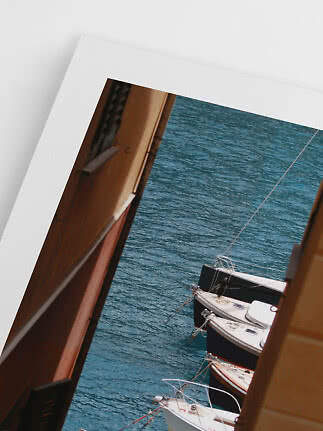 Framed photo of boats on blue water seen between buildings