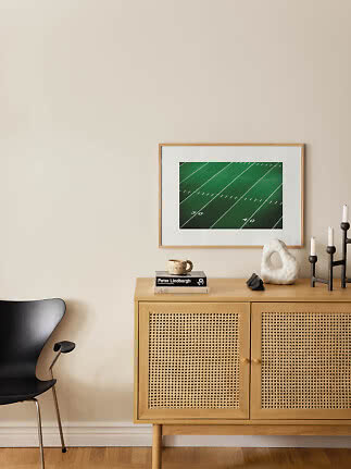 Stampa incorniciata di un campo da football americano verde sopra una credenza in legno chiaro