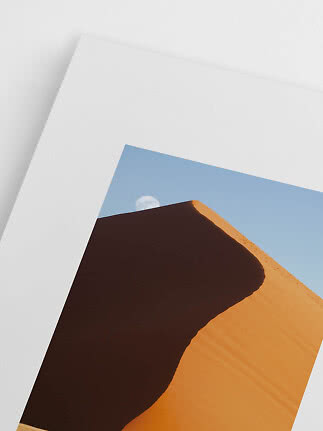 Poster mit goldener Sanddüne im Schatten und Mond vor blauem Himmel