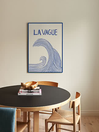 Blue and white wave poster with the text "La Vague" above a round black dining table.