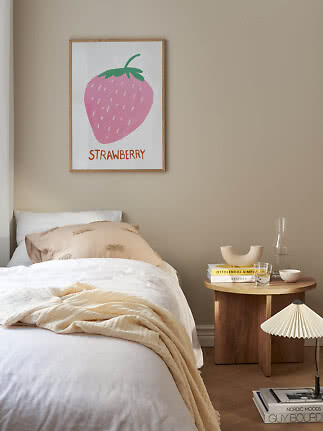 Indrammet plakat med lyserød jordbærillustration og teksten "Strawberry" over en seng