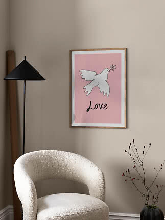 Inramad rosa poster med vit duva och texten ”Love” på en beige vägg