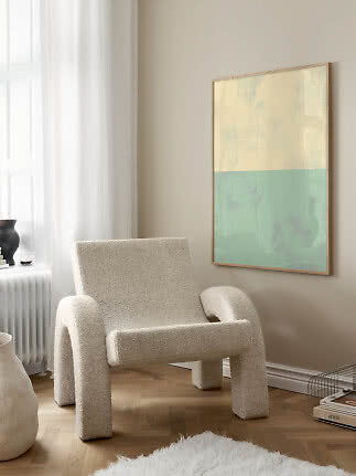 Cremefarbener Bouclé-Sessel vor abstrakter Pastell-Wandkunst in hellem modernem Raum