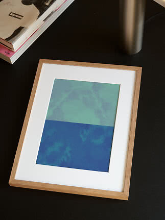 Gerahmter abstrakter Kunstdruck in Blau- und Grüntönen mit weißem Passepartout und hellem Holzrahmen