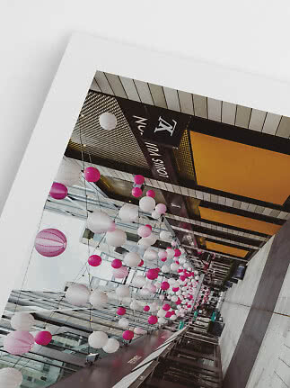 Galleria commerciale coperta con lanterne rosa e bianche sospese e insegna Louis Vuitton