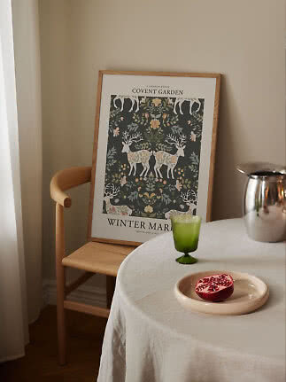 Affiche Covent Garden encadrée, motif floral et cerfs, posée contre une chaise près d'une table