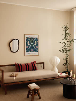 Cozy living room with wooden daybed, accent pillow, wall art, white floor lamp and potted tree