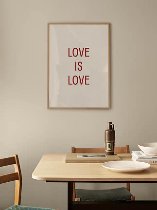 Framed “LOVE IS LOVE” poster in red text on a white background above a dining table