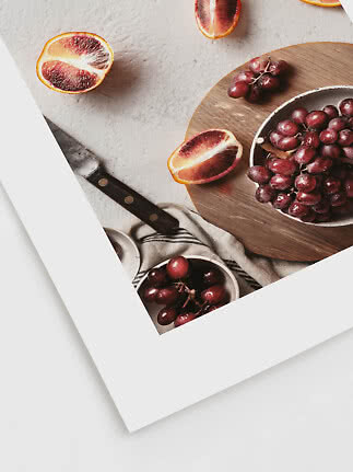 Bol de raisins rouges et moitiés d’oranges sanguines sur une planche ronde en bois