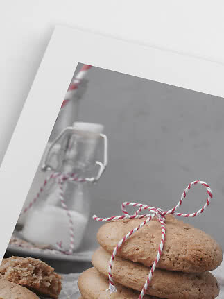 Pila di biscotti legati con spago rosso e bianco davanti a una bottiglia di latte in una foto con bordo bianco