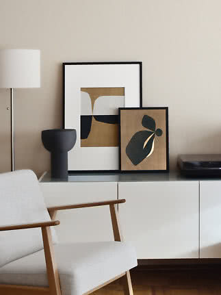 Soggiorno moderno con poltrona, credenza e due stampe astratte incorniciate