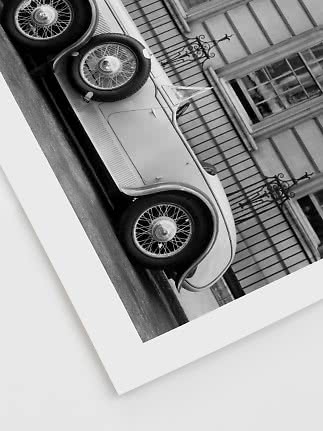 Foto en blanco y negro de un coche clásico aparcado frente a un edificio