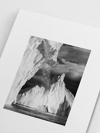 Stampa fotografica in bianco e nero di enormi iceberg sul mare sotto un cielo drammatico