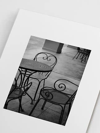 Impresión fotográfica en blanco y negro de mesa y sillas de hierro en patio de piedra