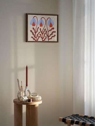 Affiche florale encadrée avec trois fleurs bleues et feuilles rouges sur mur clair