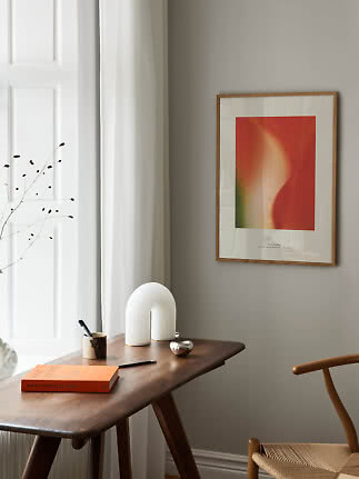 Poster astratto incorniciato sopra una scrivania in legno accanto alla finestra in una stanza minimal