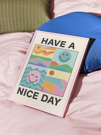 Gerahmtes buntes "Have a Nice Day"-Poster auf einem Bett mit blauen und grünen Kissen