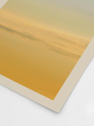 Gros plan d’une affiche jaune avec bord blanc et nuages dans une lumière dorée