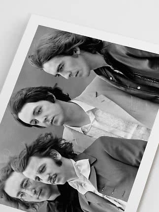 Black-and-white photo print of four people in tailored jackets and shirts with a white border.