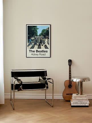Gerahmtes The Beatles Abbey Road Poster an beiger Wand über schwarzem Stahlrohrstuhl.